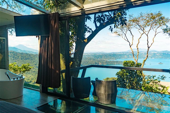 Suite con tina y terraza de vidrio frente al lago